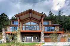 a large house sitting on top of a lush green hillside next to a forest filled with trees