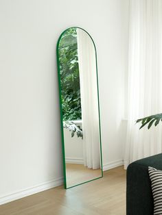 a large mirror sitting on top of a wooden floor next to a green couch in a living room