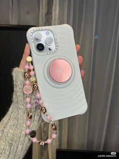 a person holding up a cell phone case with beaded charms on the front and sides