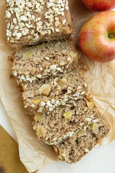 sliced loaf of oatmeal apple bread next to two apples on wax paper