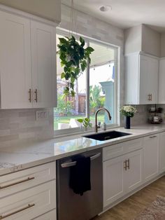 a clean kitchen with white cabinets and stainless steel dishwasher in the center island