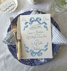 a blue and white table setting with silverware, napkins, and place settings