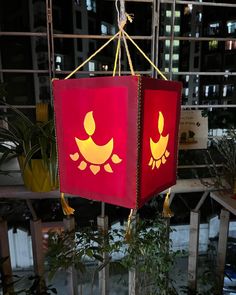 two red lamps hanging from the ceiling in front of a building with windows and plants