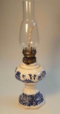 an old fashioned lamp with blue and white designs on the bottom, sitting in front of a white background