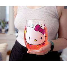 a woman holding a hello kitty wine glass in her hand