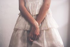 a woman in a white dress holding her hands together