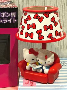 a hello kitty lamp sitting on top of a red chair next to a pink box