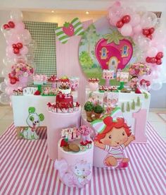 a table with pink and white balloons, cake and decorations on top of it at a birthday party