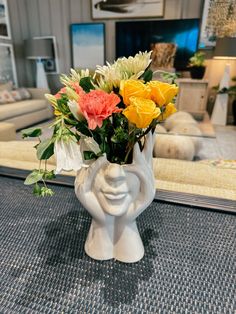 a vase filled with colorful flowers on top of a blue carpeted floor in a living room