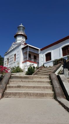 an old building with steps leading up to it and a light house in the background