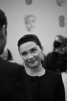 a black and white photo of a woman in a suit smiling at the camera while standing next to a man