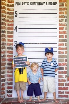 three young boys standing in front of a sign that says finey's birthday lineup