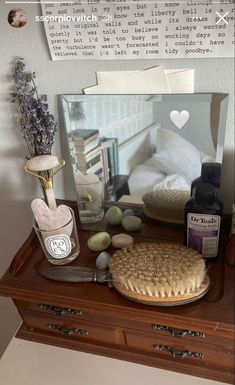 a wooden dresser topped with lots of clutter and personal care items next to a mirror