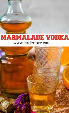 there is a bottle of marmalade vodka next to two glasses and oranges