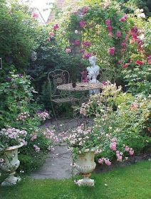 the garden has many flowers and plants around it, including roses in vases on the table