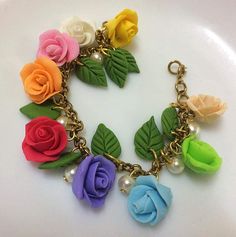 multicolored roses and pearls are attached to a gold - plated chain bracelet