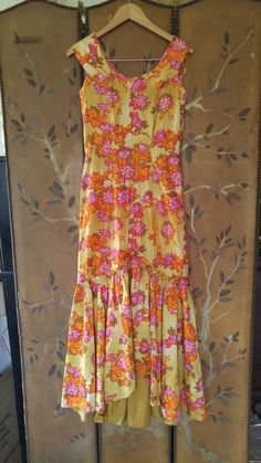 "Gorgeous 70s maxi Hawaiian dress in yellow ochre colour with orange and pink and mustard coloured flower print. The dress is long maxi length with fishtail hem which opens up in the middle between hem curtain. Fitted waist and bust. Collar goes around and over shoulders and ends at the back in two pointed 'collars. Zip up at back. Made by Liberty House, made in Hawaii, Kailua, Downtown Waialae By Hawaiian Casuals arm hole to arm hole 17\" (bust 34) waist 28\", hips 34\", dress length 55\"" Yellow Floral Print Floor-length Maxi Dress, Yellow Retro Maxi Dress For Spring, Vintage Floral Print Floor-length Maxi Dress, Retro Yellow Maxi Dress, Retro Yellow Maxi Dress For Spring, Vintage Yellow Floor-length Dress, Orange Floral Print Maxi Dress, Orange Floral Print Floor-length Maxi Dress, Yellow Retro Maxi Dress