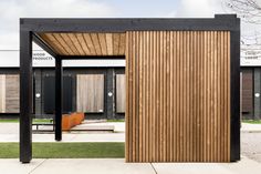 a wooden structure sitting on top of a sidewalk next to a grass covered park area