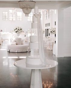 a white wedding cake sitting on top of a table next to a chandelier