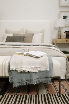 a bed with a book on top of it next to a striped rug and lamp