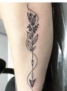 a tattoo on the leg of a woman with an arrow and flowers in its center