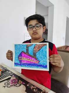 a young boy holding up a drawing in front of his face