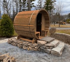 a wooden barrel sauna sitting on top of a pile of rocks