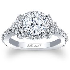 a white gold engagement ring with diamonds on the band and an oval center stone surrounded by round