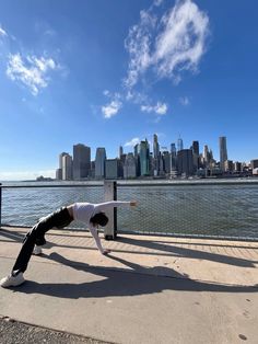 a person doing a handstand in front of a body of water with a cityscape in the background