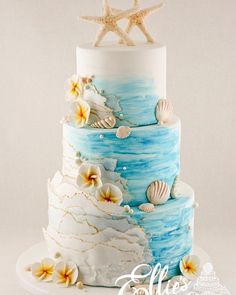 a three tiered cake decorated with seashells and starfish