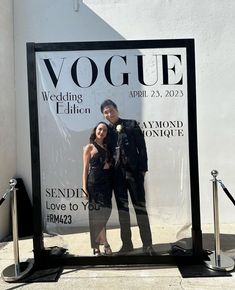 a man and woman are standing in front of a sign for a fashion show that is going on