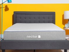 the nectar mattress is on display in front of a yellow wall with a clock and lamp