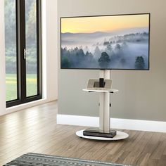 a flat screen tv sitting on top of a white stand in front of a window