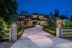 a large house that is lit up at night with lights on the front and driveway