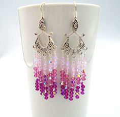 a pair of earrings with pink, purple and silver beads hanging from it's hooks