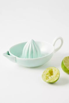 limes and a bowl on a white surface with one cut in half to show the inside