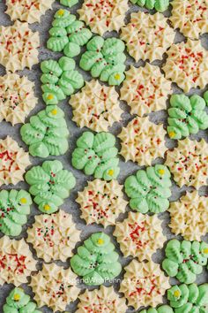 green and white cookies with sprinkles in the shape of leaves on a baking sheet