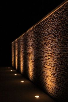 a row of lights that are on the side of a brick wall in the dark