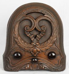 an ornately carved wooden plaque with two black beads on the front and bottom part