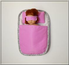 a doll is laying in a pink sleeping bag