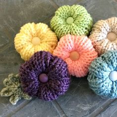 four crocheted flowers sitting on top of a stone floor next to each other