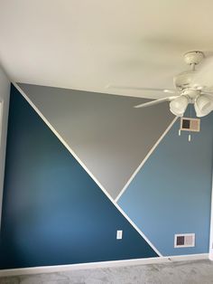 a ceiling fan in a room with blue and gray paint on it's walls