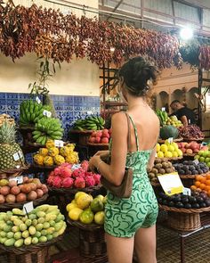 a woman standing in front of a display of fruits