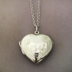 40mm L x 26mm W Solid Sterling Silver LocketOptional sterling silver 2mm cable chain.LARGE ENGRAVED STERLING SILVER HEART LOCKETThis gorgeous heart locket is artfully engraved with a delicate vintage floral pattern on both sides.The large space inside accommodates photos, a lock of hair or fur, or a love note. We do not directly personalize this locket but you may add personalized charms separately.CHOOSE YOUR FINISHThis item comes in a high gloss shiny finish (shown) or a soft matte finish. The Engraved Heart Locket Necklace For Wedding, Heart Shaped Engraved Locket Necklace For Wedding, Wedding Heart Charm Locket Necklace, Wedding Round Locket Necklace With Heart Charm, Engraved Medallion Heart Necklace For Valentine's Day, Heart-shaped Engraved Jewelry For Formal Occasions, Silver Heart-shaped Etched Necklace, Etched Heart Silver Necklace, Engraved Heart-shaped Wedding Jewelry