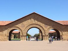 people walking and riding bikes in front of an archway