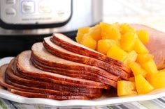 ham and pineapple slices on a white plate next to an instant pot pressure cooker