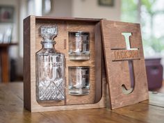 an empty glass bottle and two shot glasses in a wooden box