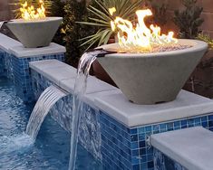 an outdoor fire pit in the middle of a pool with water flowing out of it