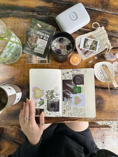 a person sitting at a table with an open book and various items on top of it