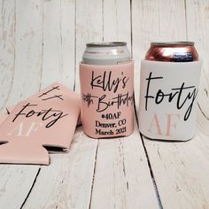 two pink and white can coolers sitting next to each other on a wooden table